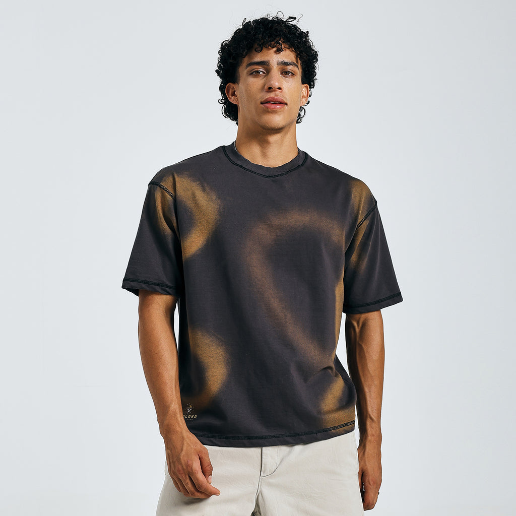 Black tie-dye mandala tee in urban casual style, walking in daylight with beige shorts.
