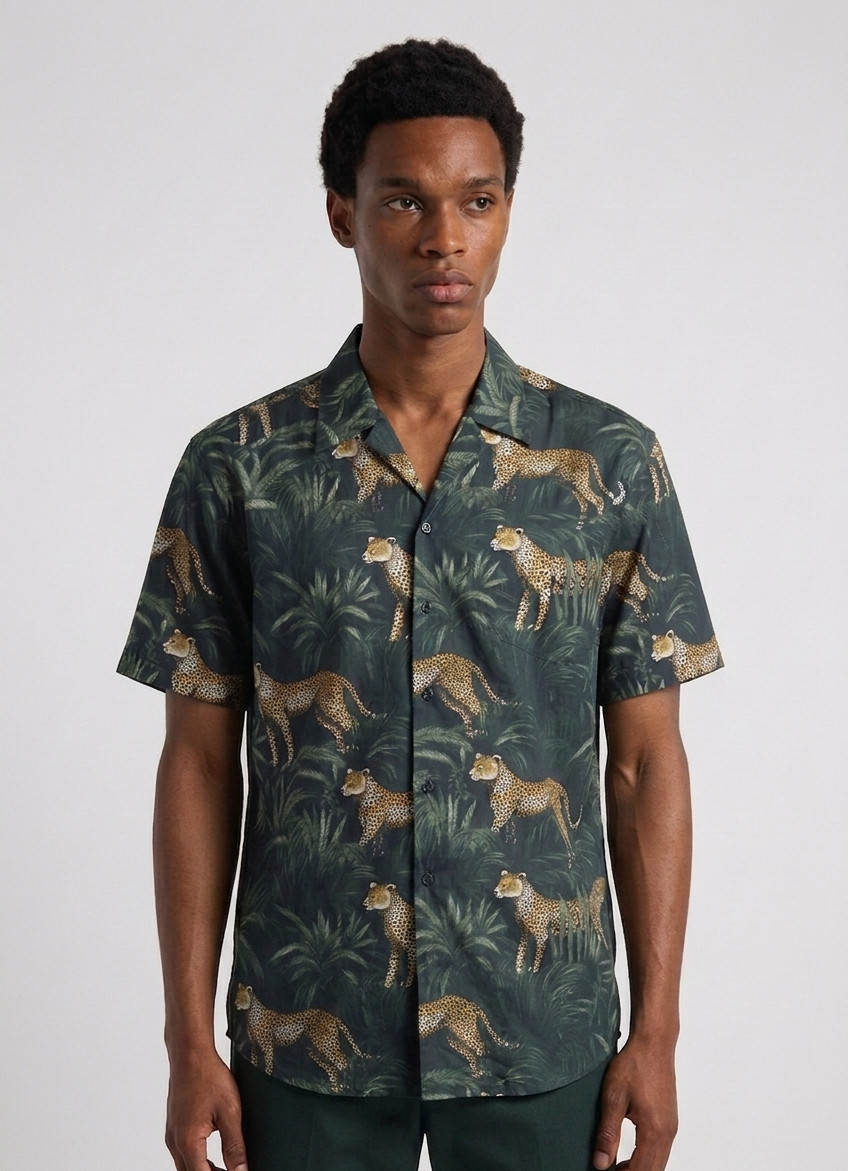 Man wearing a patterned shirt with leopards and foliage on a plain background