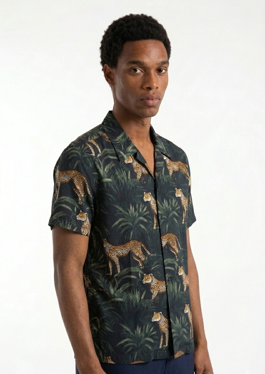 Man wearing a dark green shirt with animal print on a white background