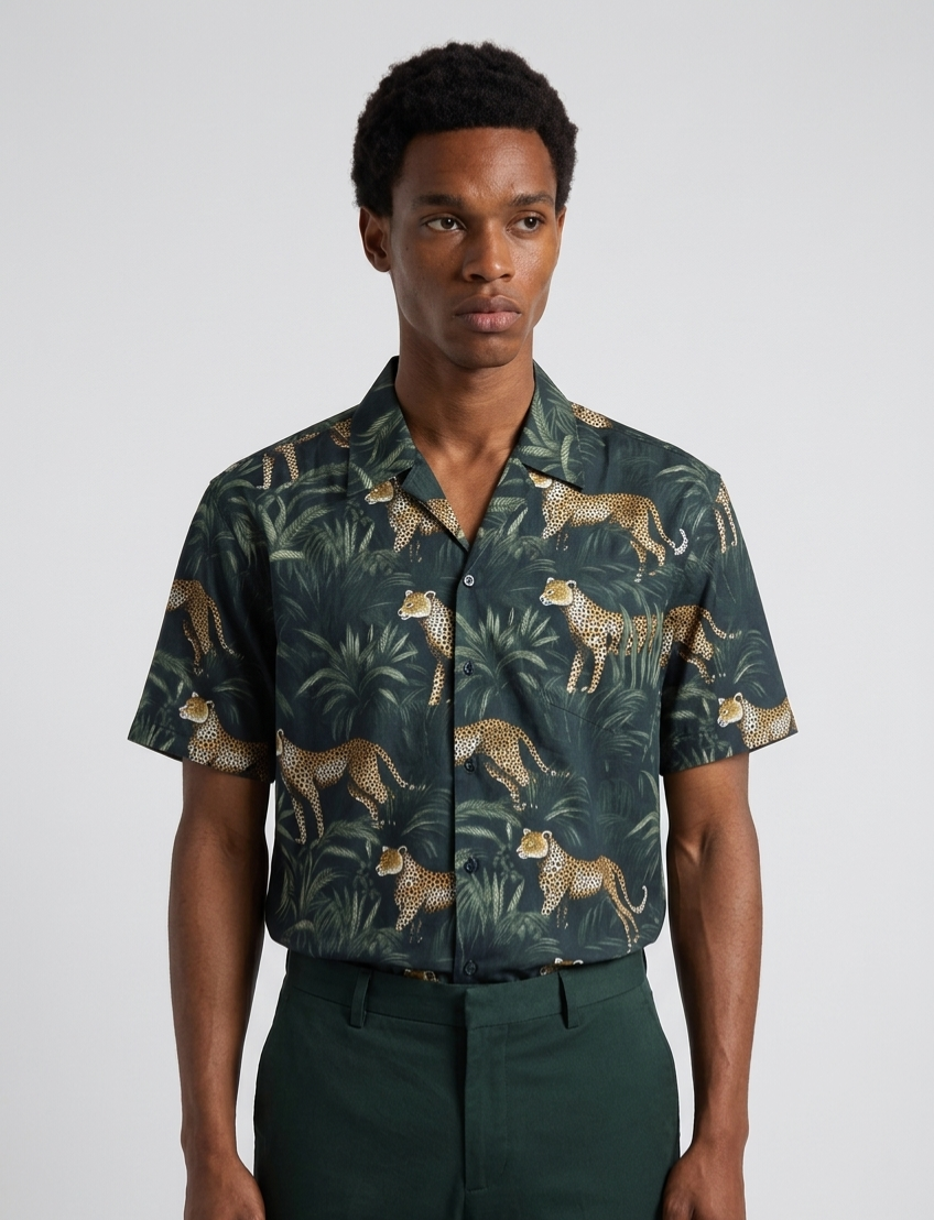 Man wearing a patterned shirt with leopards and foliage on a plain background
