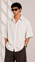 Man wearing a white striped shirt and sunglasses against a neutral background