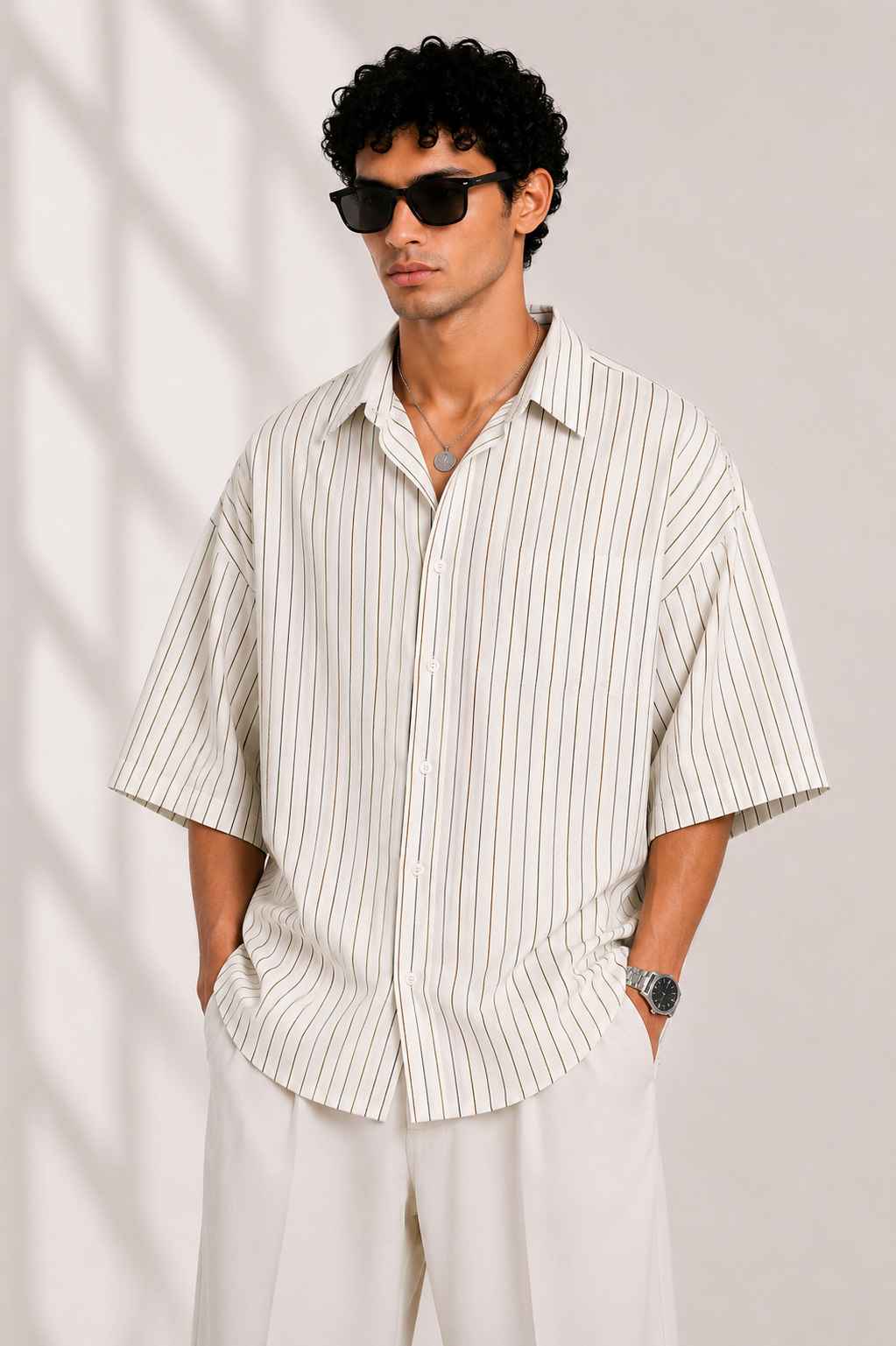 Man wearing a striped shirt and sunglasses against a plain background