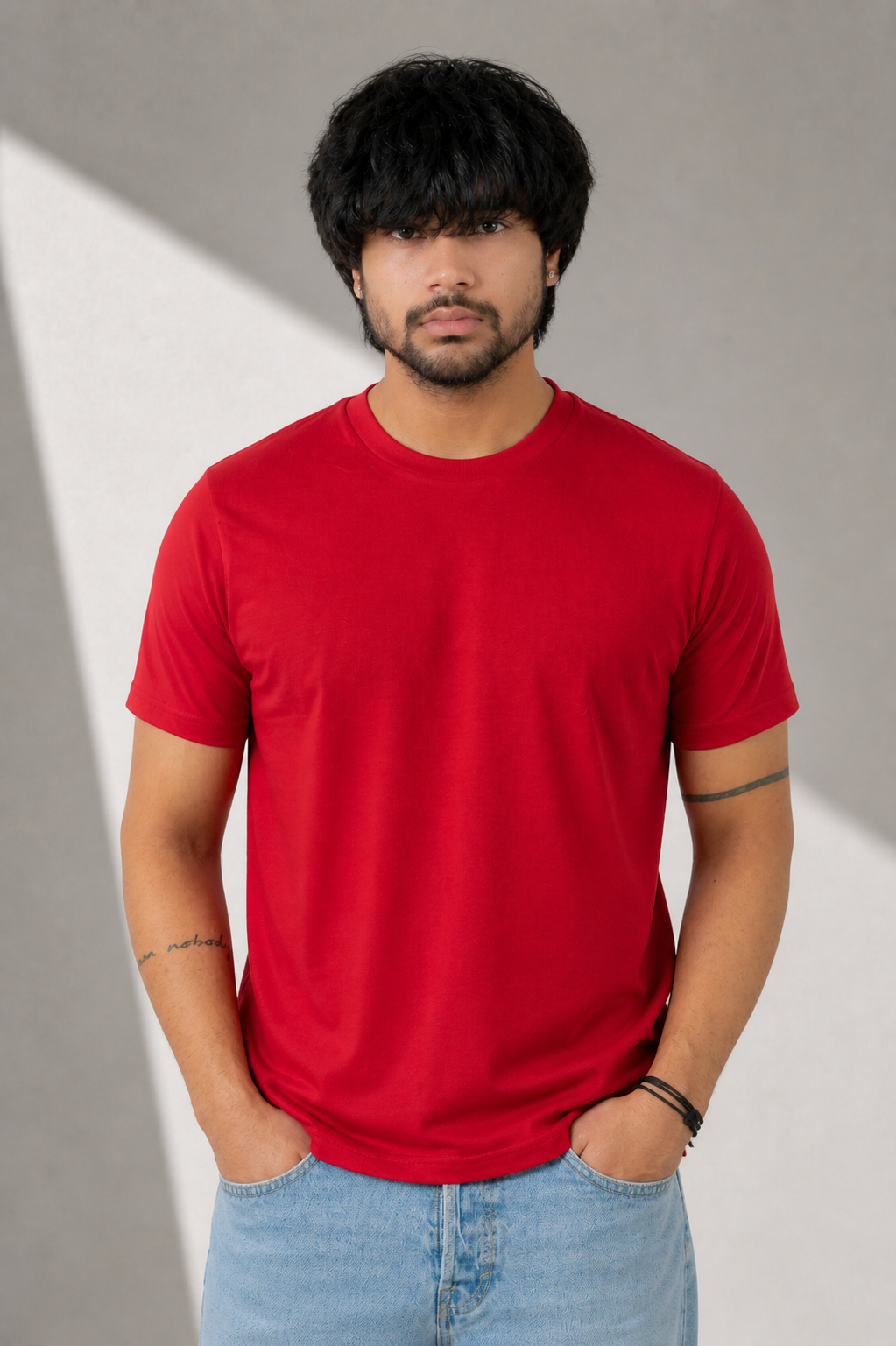 Person wearing a red t-shirt and blue jeans against a gray background