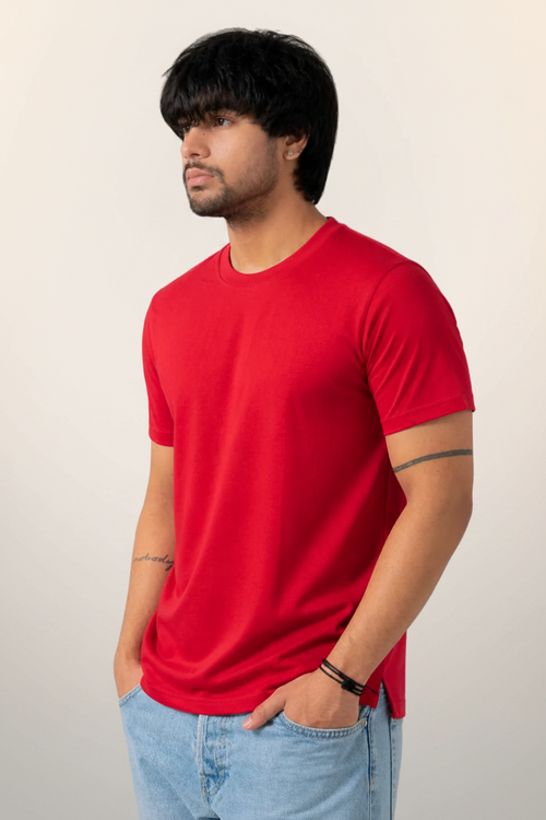 Man wearing a red t-shirt and light blue jeans against a neutral background