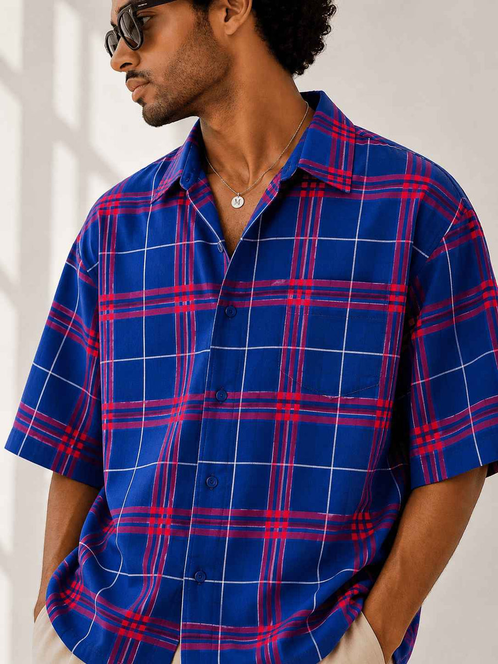 Man wearing a blue and red plaid shirt against a white background