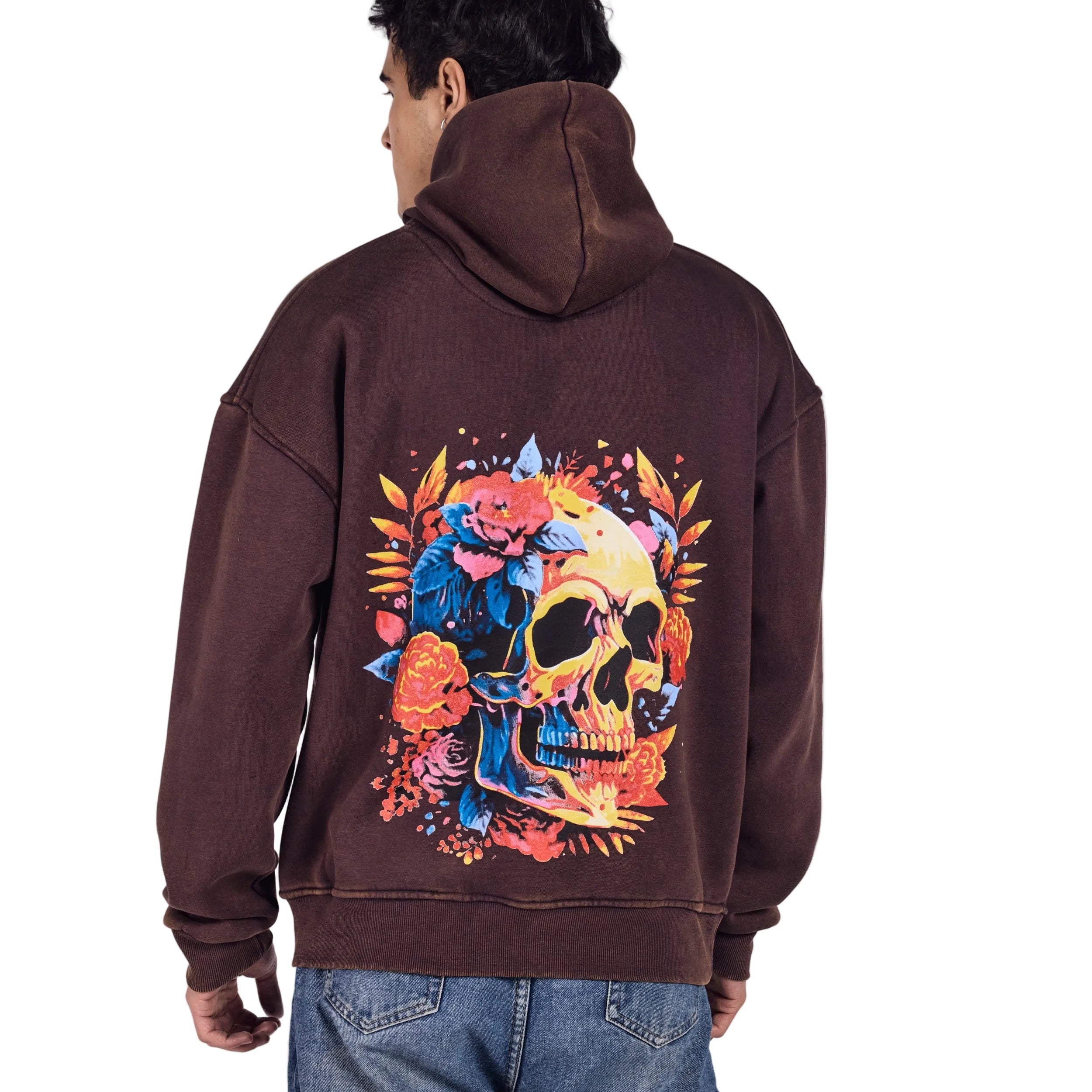Person wearing a brown hoodie with a colorful skull design on the back against a white background