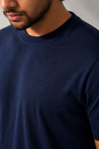 Man wearing a navy blue t-shirt against a neutral background