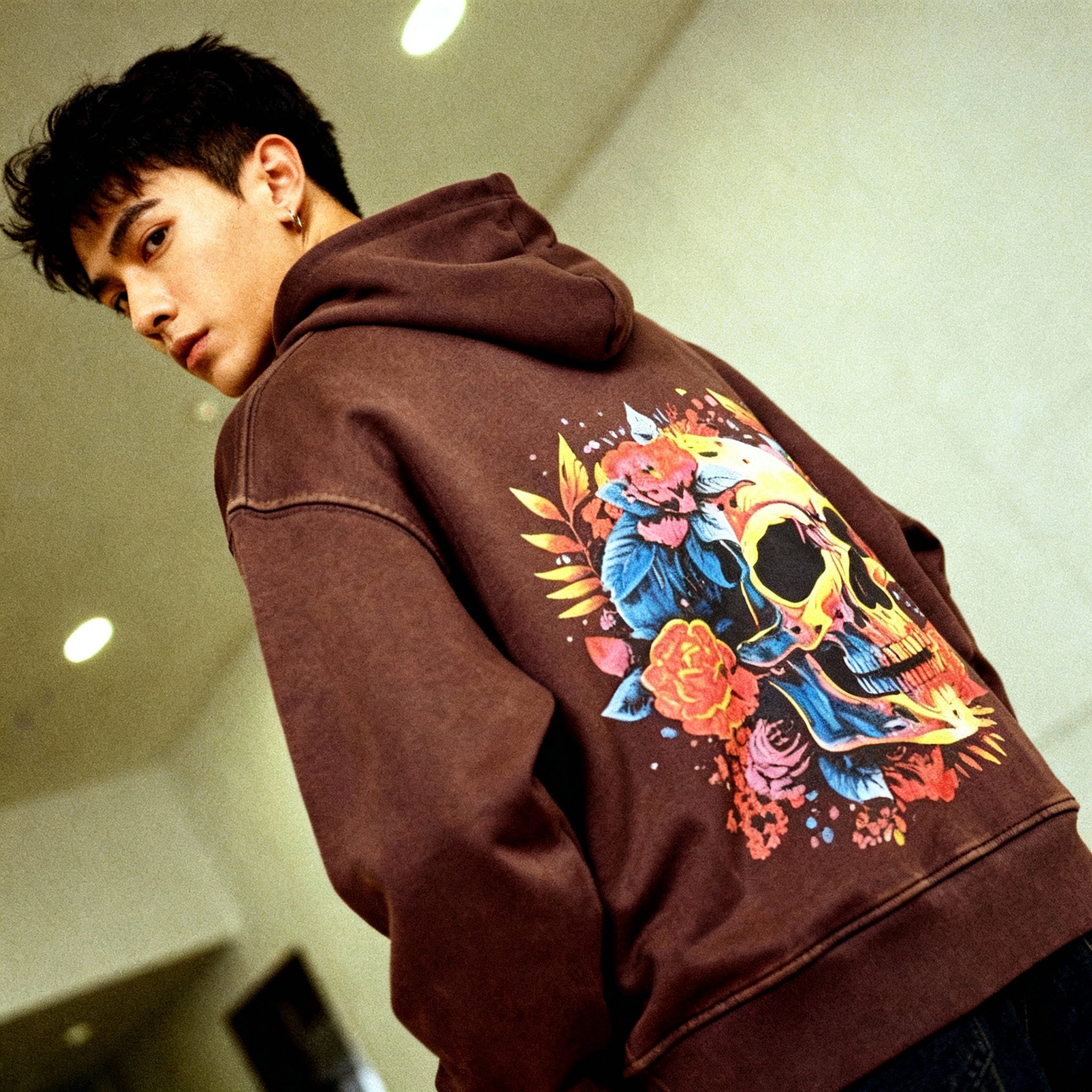 Person wearing a brown hoodie with a colorful skull design on the back.
