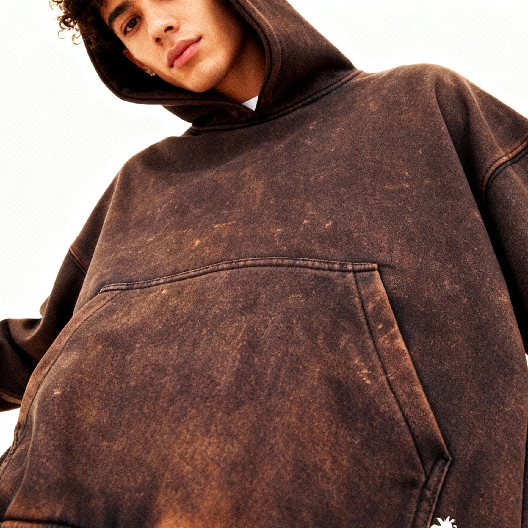 Person wearing a brown distressed hoodie with a logo on a white background