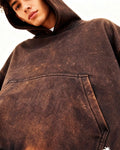 Person wearing a brown distressed hoodie with a logo on a white background