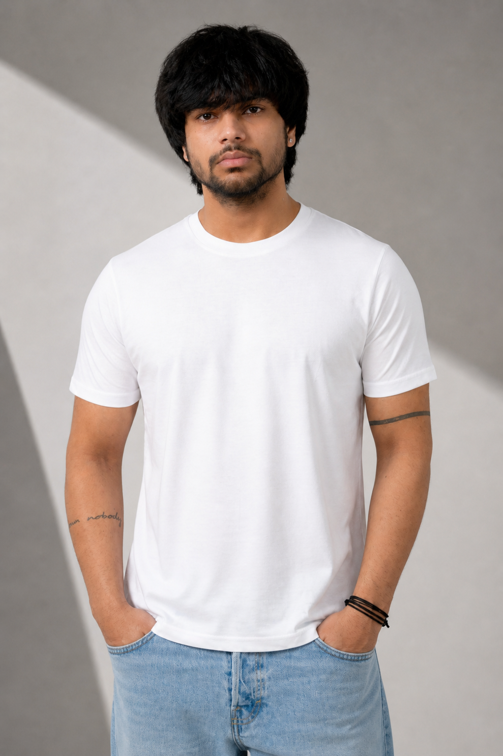 Person wearing a plain white t-shirt and light blue jeans against a gray background