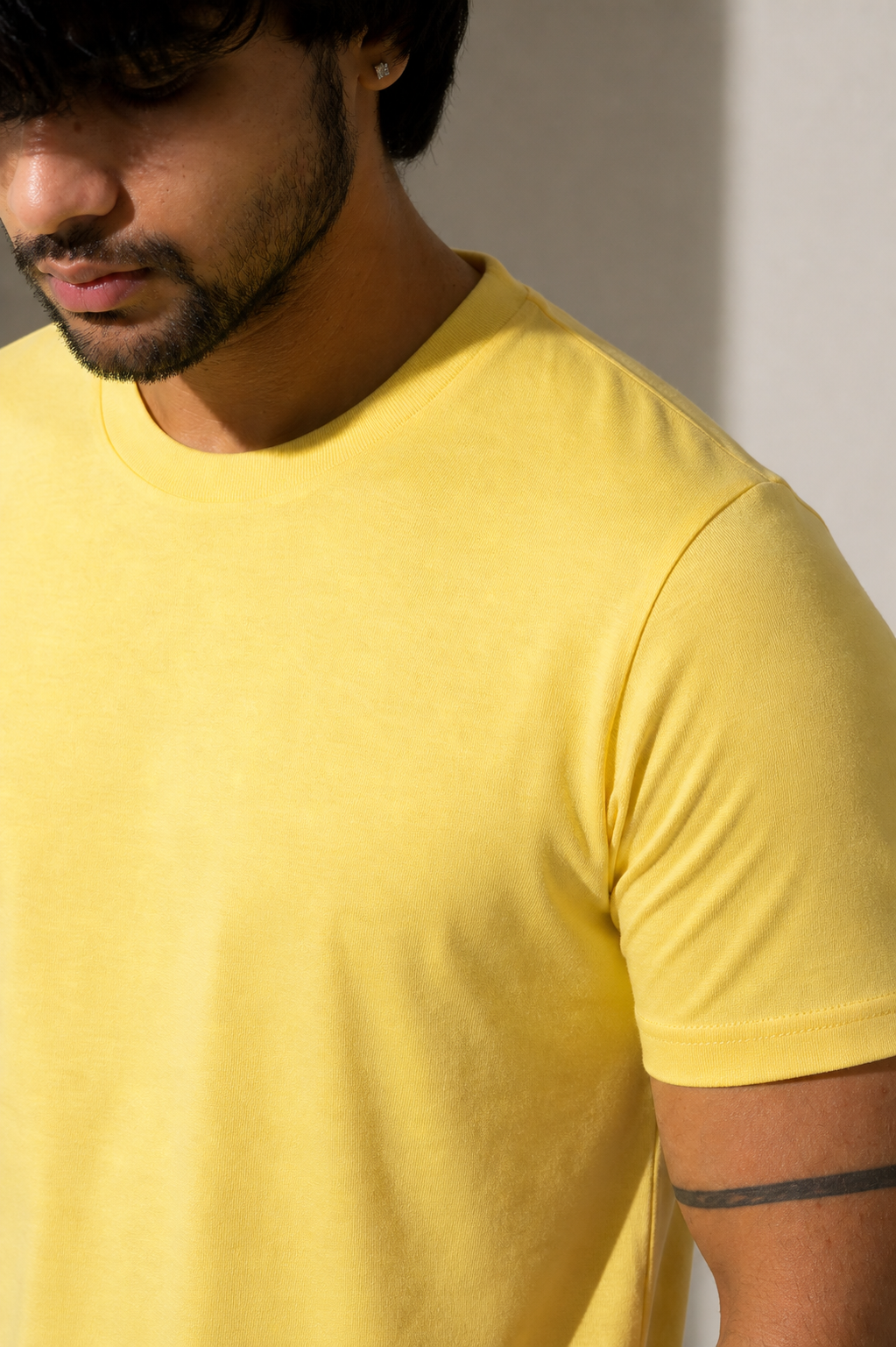 Man wearing a yellow t-shirt against a neutral background