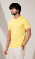 Man wearing a yellow t-shirt and white pants against a plain background