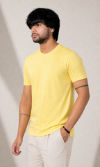 Man wearing a yellow t-shirt and white pants against a plain background